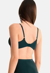 Groene bh met verstelbare bandjes en een gladde textuur, met een haaksluiting aan de achterkant en kantaccenten langs de zijkanten.
