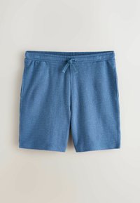 Shorts en maille texturée bleue avec ceinture élastique et cordon à l'avant sur fond clair uni.