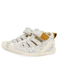 Zapatos blancos para niños con patrones de dinosaurios azules, asegurados con correas de Velcro, puntera redondeada y un acento de cuero marrón en el talón.