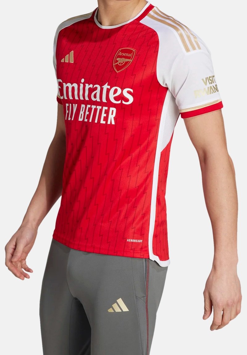 Red football jersey with a zigzag texture, white sleeves, and gold accents. Logos for Emirates and Arsenal displayed prominently.