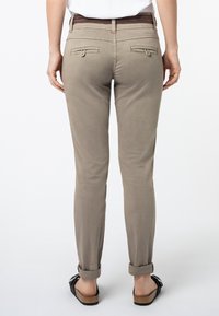 Lichtbruine slim-fit broek met een geweven bruine riem, voorzien van twee achterzakken en opgerolde boorden, gemaakt van een gladde stof.