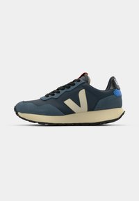Sport sneaker with blue and navy upper, beige accents, black laces, textured material, and a rubber sole with a slight heel.