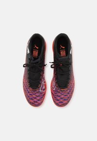 Buty sportowe z wielokolorowym, spiralnym wzorem w odcieniach czerwieni, fioletu i czerni, o gładkiej teksturze i czarnymi sznurowadłami.