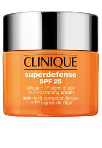 Clinique Superdefense SPF 25 kräm i en genomskinlig orange burk med ett silverlock. Texten på etiketten framhäver fördelarna mot trötthet och åldrande.