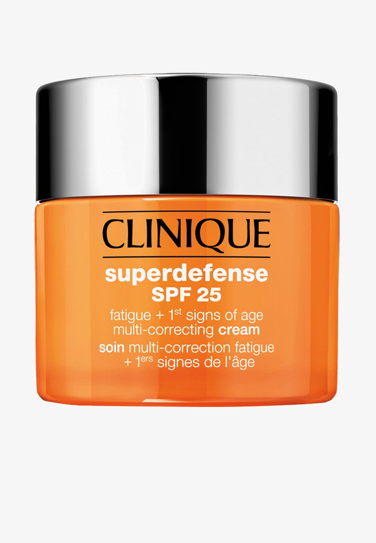 Clinique Superdefense SPF 25 krem i en gjennomskinnelig oransje krukke med et sølvfarget lokk. Teksten på etiketten fremhever fordeler mot tretthet og aldring.