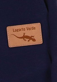 Marine stof met een rechthoekige tan leren patch waarop "Lagarto Verde" en een silhouet van een hagedis zijn afgebeeld, gestikt langs de randen.