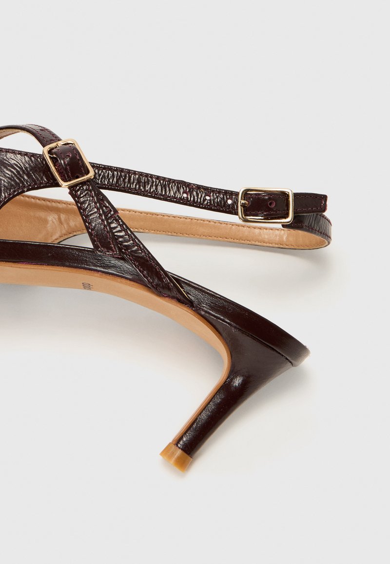 Sanda alta marrón con tacón, con parte superior de cuero texturizado, correa ajustable con hebilla de tono dorado y diseño de tacón afilado.