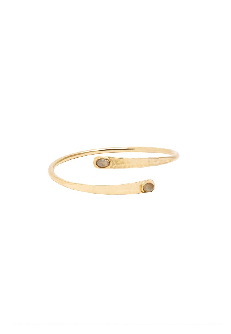 Złota bransoletka mankietowa o młotkowanej powierzchni, z dwoma smukłymi końcami, z których każdy ma mały, okrągły kamień. Prosty, otwarty design.
