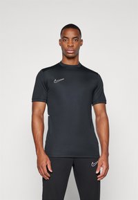 T-shirt de sport noir à manches courtes Nike, col rond, en matériau léger, avec un logo brodé blanc sur la poitrine gauche.