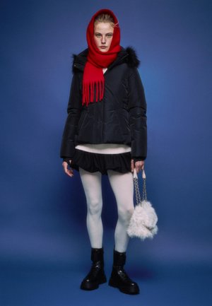 Crna pufasta jakna s krznom, crveni pleteni šal, bijeli teksturirani pulover, nabran crni suknja, bijele tajice, crne čizme s debelim potplatima i pahuljasta torba.