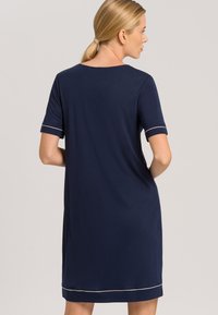 Vestido de manga corta en color navy con un corte holgado, que presenta un escote redondeado y un ribete en color claro en las mangas y el dobladillo.