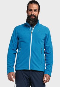 Niebieska polarowa kurtka z wysokim kołnierzem, przednim suwakiem, dwoma bocznymi kieszeniami i kontrastowym białym zamkiem błyskawicznym. Posiada logo na klatce piersiowej.