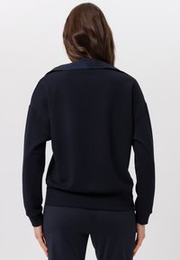 Marineblauwe sweatshirt met lange mouwen en een relaxte pasvorm, voorzien van een ronde hals en geribbelde manchetten, zachte stoffen textuur en een minimalistisch ontwerp.