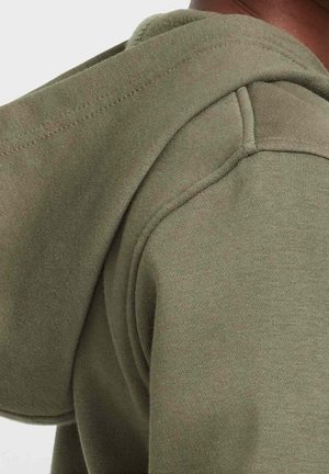 Olivengrøn hoodie med en blød tekstur, der har en hævet krave og justerbare snore. Tæt på udsigten fremhæver sømdetaljer.