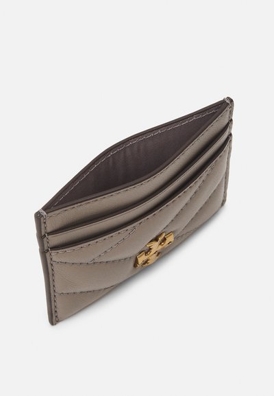 Petite housse à cartes en cuir gris avec une texture matelassée, ornée d'un emblème doré, plusieurs emplacements pour cartes, et un compartiment intérieur doublé.