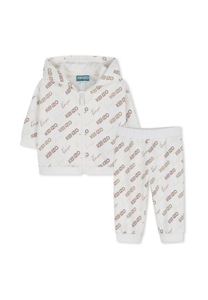Wit hoodie en broekset met ritssluiting, voorzien van een herhalend bruin en goudkleurig "KENZO" logo patroon, gemaakt van zacht materiaal met geribbelde boorden.