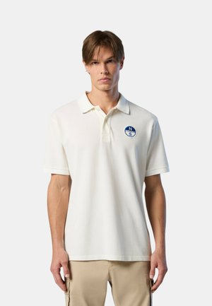 Witte polo met een kraag, korte mouwen en een blauw rond logo op de linkerborst. Gladde textuur en klassiek ontwerp.