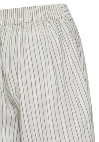 Pantalons en lin légers avec une base blanche et de fines rayures navy. Taille élastique et poches latérales visibles. Tissu texturé.
