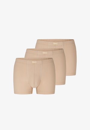Tre beige herre boxershorts med elastiske linninger stablet diagonalt på en hvid baggrund.