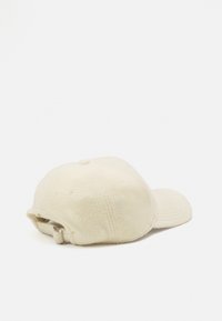 Cream-colored fleece cap with curved brim, textured finish, adjustable strap at the back, and six ventilation eyelets for breathability.
