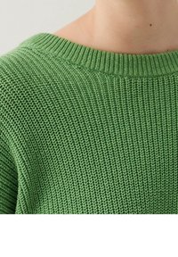 Grüner gestrickter Pullover mit einem gerippten Rundhalsausschnitt und strukturierten Mustern, der einen weichen Stoff mit lockerer Passform hervorhebt.