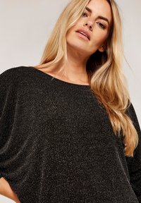 Zwarte, sprankelende sweater met een relaxte pasvorm, brede halslijn en textiel met structuur. Bevat gedrapeerde mouwen en een zachte, glanzende afwerking.