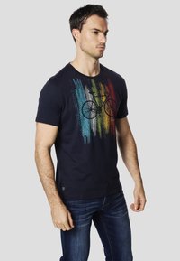 T-shirt in cotone blu navy con grafica di una bicicletta e strisce verticali colorate in blu, giallo e rosso; scollo rotondo, maniche corte.