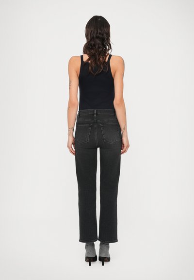 Mustad kõrge vöökohaga sirgete sääreosadega teksad, millel on tagataskud ja sile pind, kombineeritud tumelilla varrukateta pealsega.