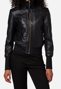 Černá kožená bomber bunda s vysokým límcem, zapínáním na zip, žebrovanými manžetami a lemem, s hladkou texturou a minimálními kovovými detaily.