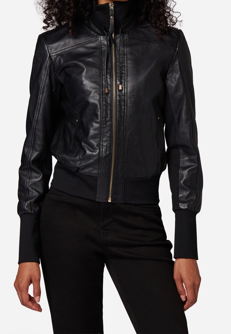 Černá kožená bomber bunda s vysokým límcem, zapínáním na zip, žebrovanými manžetami a lemem, s hladkou texturou a minimálními kovovými detaily.
