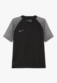 Camiseta deportiva negra de manga corta con un detalle de tela gris con estampado en los hombros. Presenta un escote redondo y un logo de Nike.