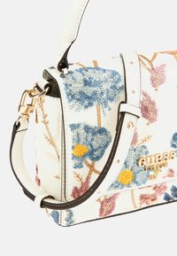 Bolso blanco con textura y bordado floral en azul, rosa y amarillo. Cuenta con herrajes dorados y una correa para el hombro desmontable.