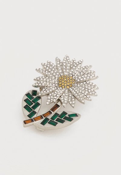 Broche floral en argent avec des cristaux clairs formant les pétales, des cristaux jaunes pour le centre de la fleur, et des pierres rectangulaires vertes et brunes sur les feuilles.