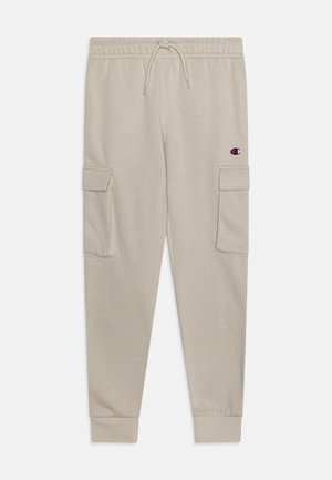 Pantalons cargo beiges avec une taille élastique et un cordon de serrage, featuring des poches latérales et une patch logo sur la cuisse gauche. Texture de tissu douce.