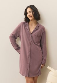 Camicia da notte a maniche lunghe color malva, realizzata in materiale morbido con chiusura davanti a bottoni, colletto e una tasca sul petto per i dettagli.