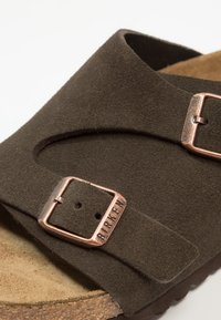 Brown suede sandal featuring two adjustable metal buckles, contoured cork footbed, and textured rubber sole.