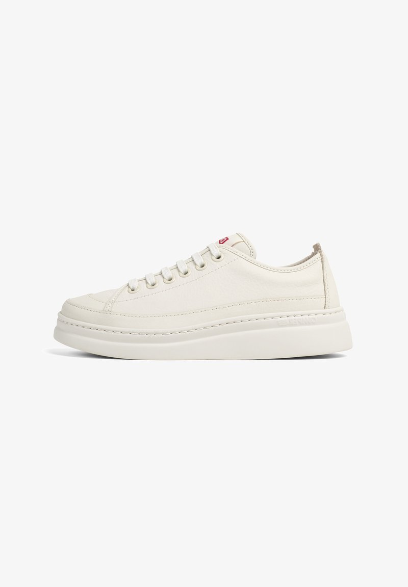 Weiße Ledersneaker mit flachen Schnürsenkeln, gepolstertem Schaft und einer dicken weißen Gummisohle. Minimalistische Nähte und ein rotes Logo als Akzent.