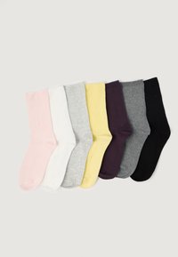 Șapte perechi de șosete simple de tip crew în roz pastel, alb, gri deschis, galben, mov închis, gri mediu și negru, așezate una lângă alta.
