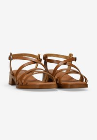 Sandalias de cuero marrón con múltiples correas entrelazadas, una hebilla ajustable en el tobillo y un tacón bajo en bloque. Forro interior de suave ante.