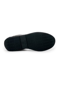 Black rubber shoe sole with textured grip pattern and branding. Flat shape designed for stability and durability. Minimalistic design.