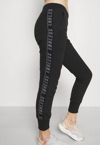 Svarta joggingshorts i slim fit, med en vertikal textdesign "ENDLESS" på sidan. Tillverkade av mjukt material med ribbade anklar.