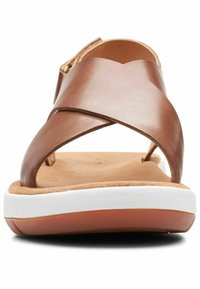 Sandalo in pelle marrone con cinturini incrociati, soletta in suede color sabbia, intersuola bianca e suola in gomma marrone. Dispone di una fibbia laterale per la regolazione della vestibilità.