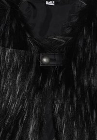 Czarna kamizelka z futerkiem ekologiczny o błyszczącej fakturze, z paskiem skórzanym i okrągłym, fakturowanym metalowym guzikiem jako zapięciem.