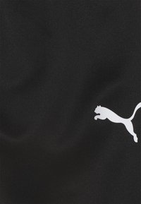 Črna tkanina z gladko teksturo in izrazitim belim logotipom Puma na desni strani. Enostavna in minimalistična zasnova.