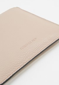 Portefeuille en cuir beige texturé avec « FOREVER NEW » embossé à l'avant, présenté sur un fond blanc.