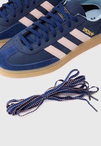 Sapatilhas de camurça azul-marinho com riscas rosas, design de atacadores e sola de borracha de goma. Inclui cordões sobressalentes trançados azuis e rosas.