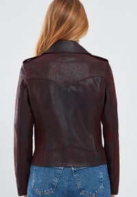 Bordeaux leren jacket met een gladde textuur, een getailleerd ontwerp en een spitse kraag. Bevat stikseldetails en is op taillehoogte gesneden.