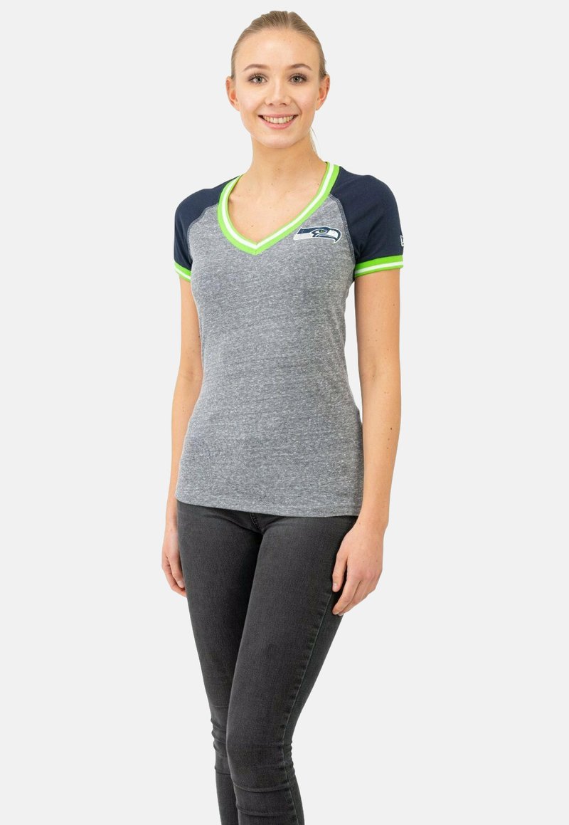 T-shirt gris à col en V avec des manches courtes bleu marine, bordures vert fluo et logo des Seattle Seahawks sur la poitrine ; fabriqué en un tissu doux et extensible.