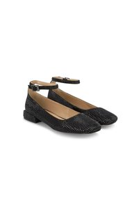 Ballerines noires tressées avec brides de cheville, bout carré et petit talon bloc. Présente une surface texturée avec un éclat subtil et un intérieur beige contrastant.