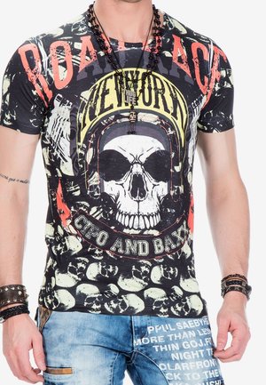 T-shirt graphique noir avec un motif de crâne, texte "New York" et un motif superposé de petits crânes. Style à manches courtes.